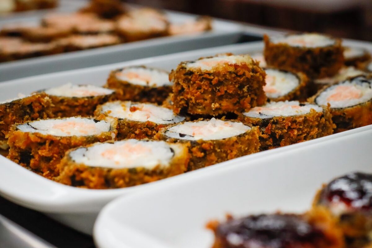A close-up of crispy fried sushi rolls presented elegantly on a white tray.