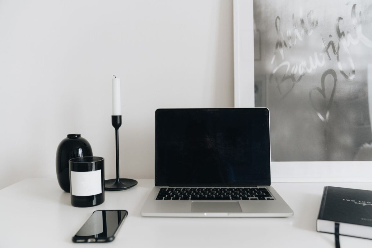 A clean and modern home office desk setup with a laptop, smartphone, and decor elements.