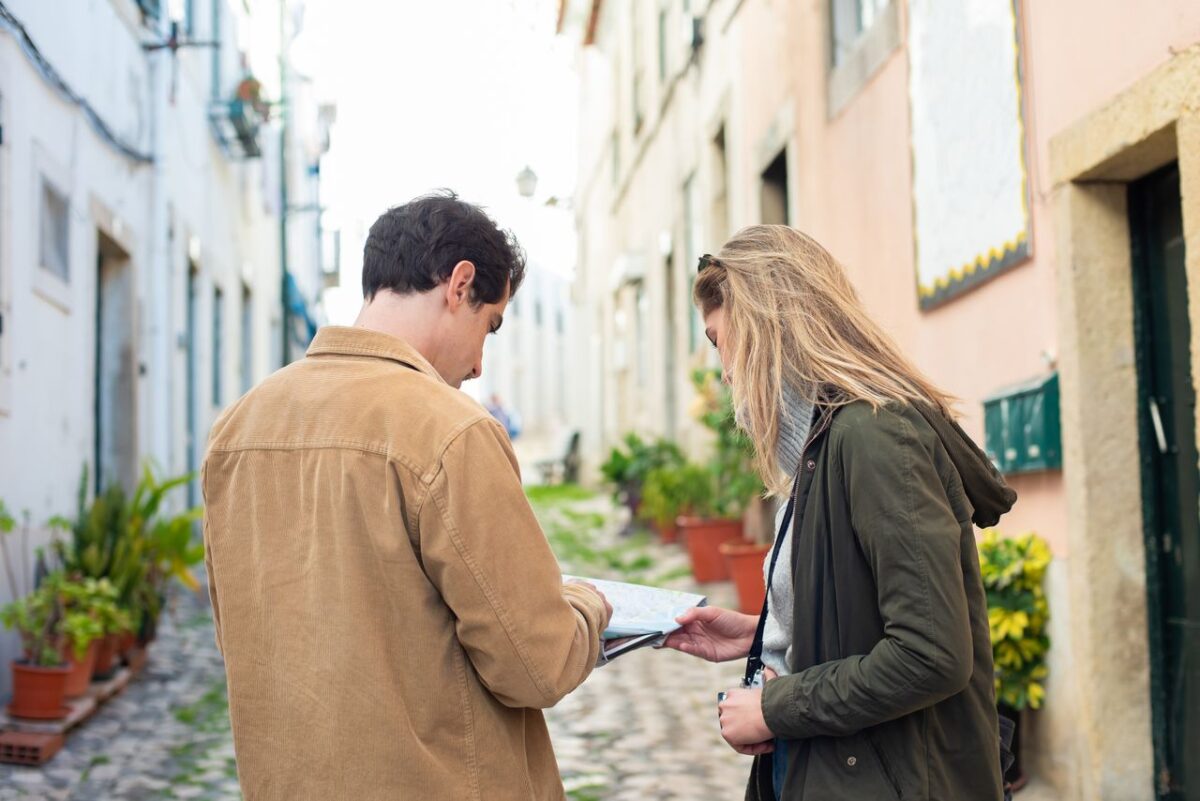 Two travelers exploring a charming European street, using a map for navigation.